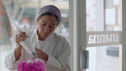 Pastry chef rotates tray and puts icing on cake with decorating bag Stock Footage