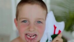 A young boy happily shows his missing front tooth and holds up his tooth-fairy pillow Stock Footage