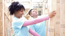 Volunteers work on construction frame on home being built for charity Stock Footage