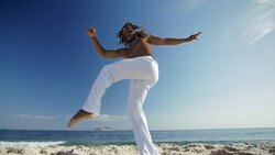 Brazilian martial artist kicks high over camera on Ipanema Beach Stock Footage