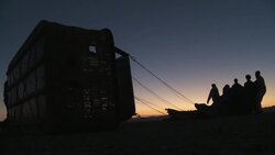 Silhouetted balloonists prepare a hot air balloon for takeoff against a glowing horizon. Stock Footage