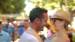 Young man lifts girlfriend up and kisses her in Brazilian marketplace Stock Footage