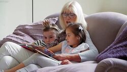 Grandmother  and Granddaughter s reading book on sofa Stock Footage
