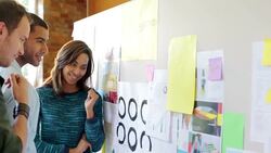 Designers reviewing proofs on board in sunny office Stock Footage