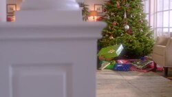 Curious young boy turns and shakes present intently in front of Christmas tree (dolly-shot) Stock Footage