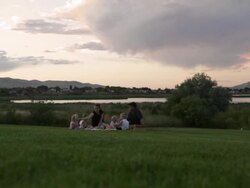 A tracking shot of a young family having a picnic by a lake on a cloudy day. Stock Footage