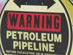 CU Sign of declaring Warning Petroleum Pipeline with reflections of nearby passing cars / Beaverton, Oregon, United States  Stock Footage