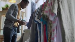 Young shop employee tags shirts in clothing store with tagging gun Stock Footage