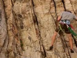 Tilt shot of a rock-climber descending from the top of a cliff. Stock Footage