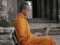 MS A Buddhist monk uses a laptop computer on the steps of an ancient temple in Angkor Wat / Siem Reap, Cambodia Stock Footage