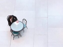  HA Businessman sitting at table on empty tiled floor, talking on cell phone and studying document / Seattle, Washington, United States Stock Footage