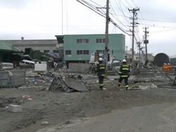 Destruction caused by tsunami after magnitude 9 Tohoku earthquake, north east Japan, March 2011. Fire crews walk through debris strewn streets in Ishinomaki City port, Miyagi Prefecture Stock Footage