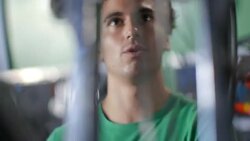 Bike shop mechanic spins bicycle wheel on truing stand and explains process to customer Stock Footage