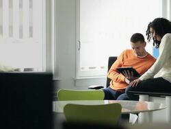 MS businessman and businesswoman sitting at workstation in office working on digital tablet  Stock Footage