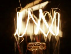Timelapse close up zoom out and track up of an electric light bulb filament flickering on and off Stock Footage