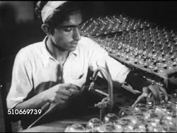 1953: PROGRESS REPORT ON PAKISTAN: Pakistani male on factory line, pulling glass light bulb out of rotation w/ hand tool, MS Male soldering end of completed light bulbs. Instructional Video