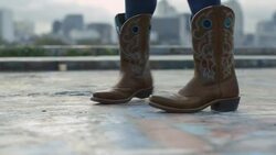 Close-up of cowboy boots dancing overlooking Austin, Texas city skyline Stock Footage