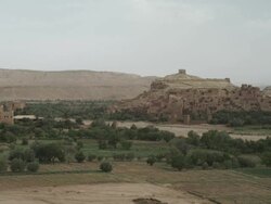 Vegetation and agricultural land surround dwellings clustered on a Moroccan hillside. Stock Footage