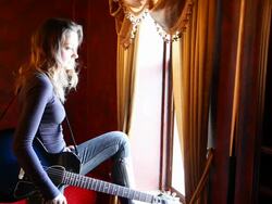 Young Woman Turns to Window, Plays Guitar Stock Footage
