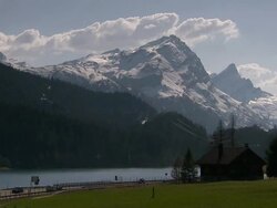 Wide Shot static - Clouds float above snow covered mountains near an alpine lake. / Germany Stock Footage