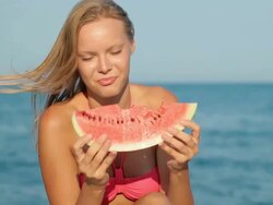 Attractive blond woman eating watermelon on beach Stock Footage