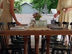 MS two sisters setting table for dinner on front porch of home Stock Footage