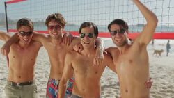 Playful young men cheering at beach volleyball net Stock Footage