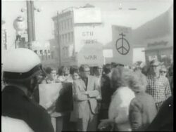 A crowd of civilians sits in front of the Military Induction Center; police officers arrest protesters. News Clip