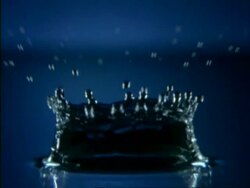 High Speed BCU water drop splashing into dark blue water, side view Stock Footage