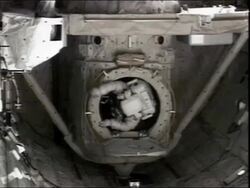High angle medium shot astronaut climbing out of a hatch on the International Space Station Stock Footage