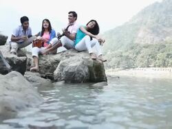 Group of friends enjoying music at riverbank Stock Footage