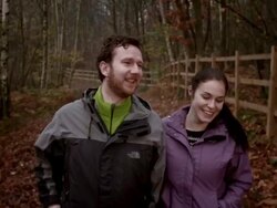 MS handheld following young couple walking through woods Stock Footage