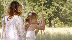 SLO MO Mother braiding daughters hair on swing Stock Footage