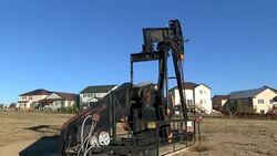 Oil well pump jack just outside the backyards of homes in Frederick, Colorado time lapse Stock Footage