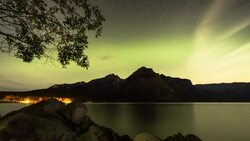 Time lapse view of aurora borealis passing overhead lake, mountains Stock Footage