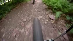 The front wheel of a bicycle follows another cyclist down a mountain path. Stock Footage