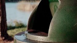 Slimy flap door on a green park service garbage trash can barrel. Stock Footage