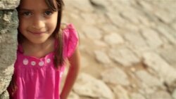 Cute young hispanic girl smiles at camera on third-world street corner Stock Footage