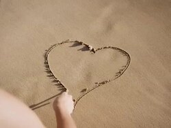 Woman painting heart shape in sand Stock Footage