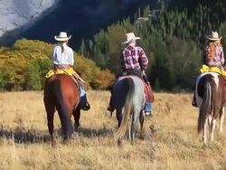 Cowboy and two cowgirls riding towards the mountains Stock Footage