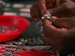 Close up of a pair of hands beading with a needle and thread with some completed beadwork on the table Stock Footage