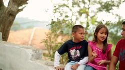 Little sister speaks animatedly with teenage brother on stone-wall (dolly-shot) Stock Footage