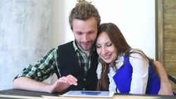 Happy couple with tablet computer sitting in cafe Stock Footage