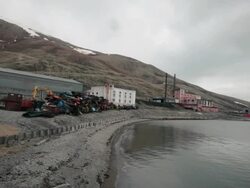 Old buildings and an old abandoned coal-fired power plant at the harbor of the abandoned Russian settlement and coal mining community Pyramiden on the archipelago of Svalbard, Norway Stock Footage
