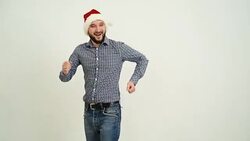 young adult beard man dancing in a hat santa claus on a grey background Stock Footage