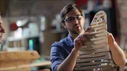 Proud woodworker demonstrates flexibility of new frame design to student Stock Footage