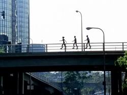 Wide shot woman and two men walking across bridge on skyrunners with buildings in background Stock Footage