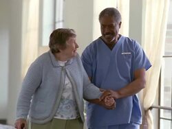 MS Senior woman walking with male nurse down hospital hallway as another man walks by / Washington State, USA Stock Footage