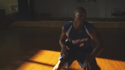 A basketball player practices with an imaginary guard in front of empty bleachers. Stock Footage