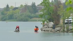 Police diver carrying orange tarp to recover body Stock Footage